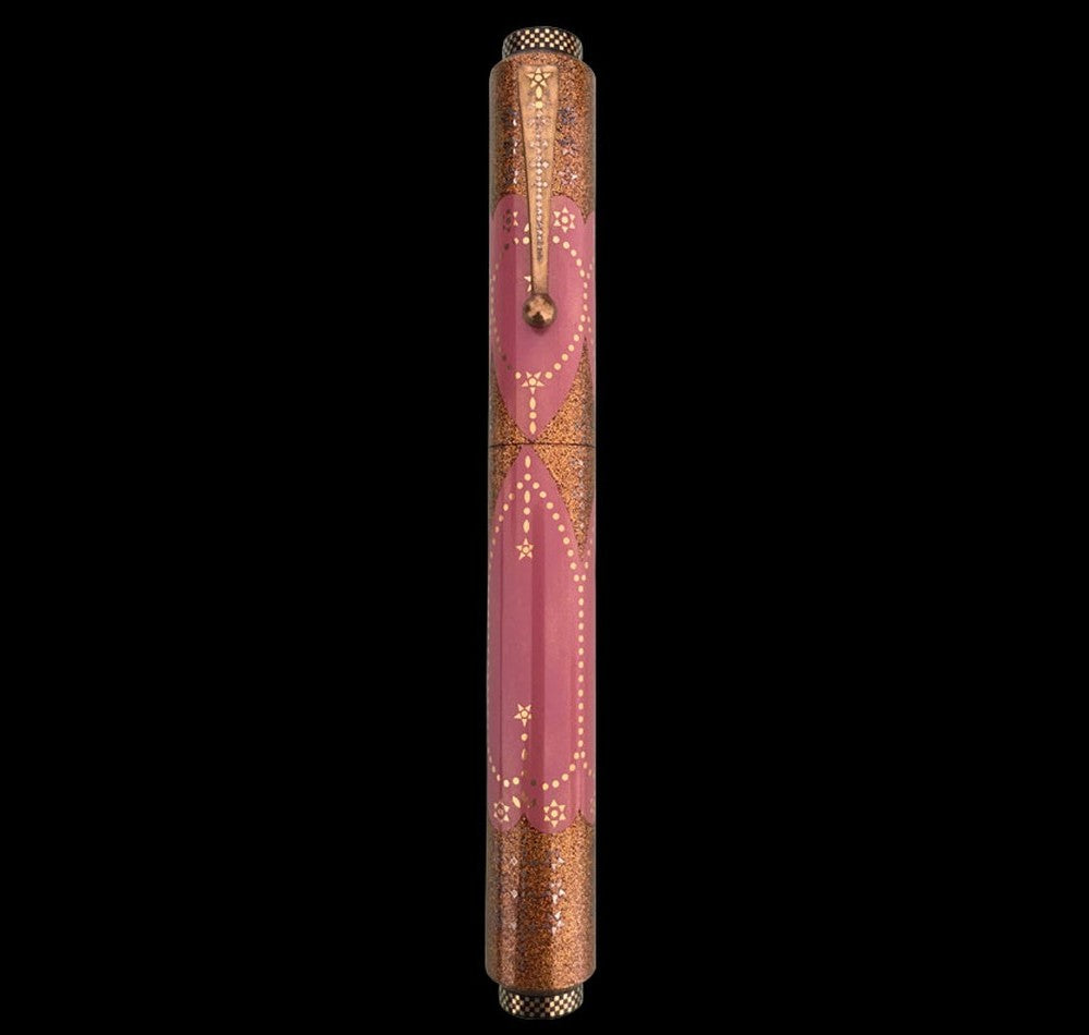 Decorative pen with pink and gold design on a black background.