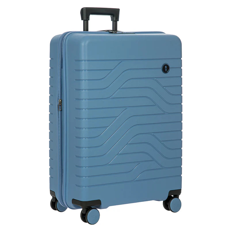 Front-angled view of the suitcase with the telescopic handle partly pulled up. Set on a white background. The suitcase is a light grey-blue with black accents, and features a design of lines on toe front and back. A small Bric's logo is placed on the top right.