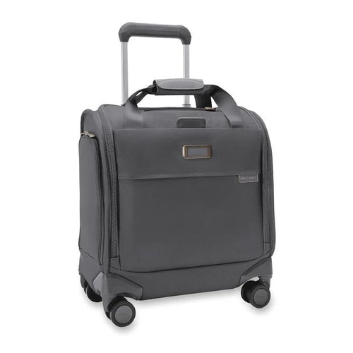 Angled front view of the steel gray baseline cabin spinner. It features a telescopic handle, a set of carrying handles at the top, and 4 spinner wheels. The leather monogram label can be embossed with up to 3 characters.
