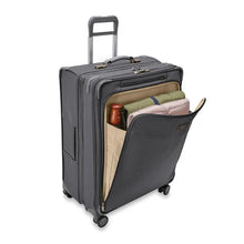 Load image into Gallery viewer, Front angled view of the suitcase with the front panel unzipped, and with some accessories organized inside. 
