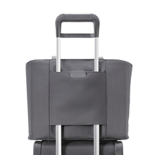 Load image into Gallery viewer, Image of the back panel shown with the attachment feature sliding over the telescoping handle of a suitcase.

