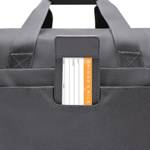 Load image into Gallery viewer, Close up to the back panel of the steel gray underseat duffle. An ID tag can be pulled from its compartment to write your name and contact information. 
