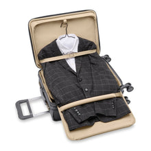 Load image into Gallery viewer, The suitcase laid down with the front panel&#39;s Tri-fold Suiter Compartment unzipped, shown holding a suit.

