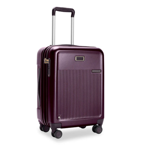 Front Angled View of the plum colored hard shell suitcase. It has a ridged front panel, and the telescoping handle partially extended.

