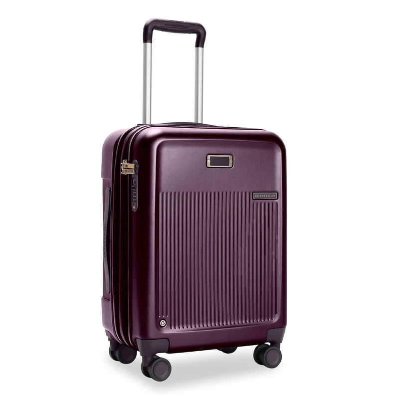 Front Angled View of the plum colored hard shell suitcase. It has a ridged front panel, and the telescoping handle partially extended.


