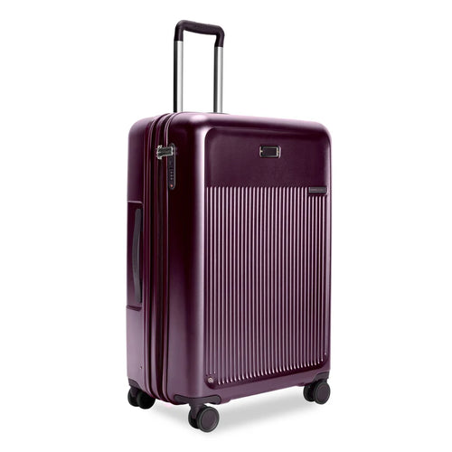 Front Angled View of the plum-colored hard shell suitcase. it has a ridged front panel, and the telescoping handle is partly extended.