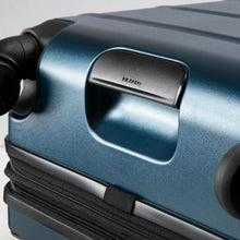 Load image into Gallery viewer, Angled bottom close up to the blue hard shell suitcase. It features a grab handle. 
