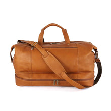 Load image into Gallery viewer, Front view of the tan leather drop bottom duffle bag. The shoulder strap is resting diagonally across the top and front. 
