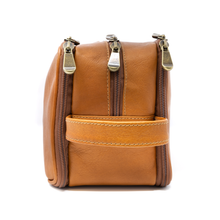 Load image into Gallery viewer, Left panel view of the tan leather zipper bag with three zipper-closing compartments and a grip handle. 
