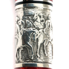 Load image into Gallery viewer, Close-up to the silver band in the pen barrel, object featuring embossed relief carvings of riders on horseback, with polished reflective surfaces and a hint of red at the bottom edge.
