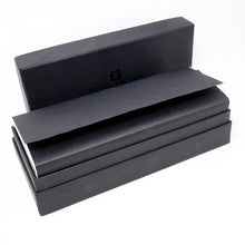 Load image into Gallery viewer, The black outer box holding the transparent presentation box, wrapped in black paper. The box lid is set behind it. 
