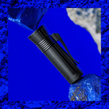Load image into Gallery viewer, Close up to the pen cap arranged between pieces of Lapis Lazuli on a blue stylized background.
