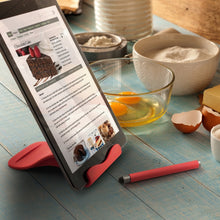 Load image into Gallery viewer, The red tablet stand holding a tablet featuring a cake recipe on a kitchen setting with ingredients.

