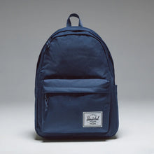 Load image into Gallery viewer, Front panel view of the navy blue backpack with a white Herschel logo tag at the bottom. 
