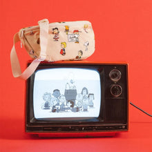 Load image into Gallery viewer, The Peanuts Pattern hip pack resting on top of a TV with a Snoopy image on a vintage TV. Set on a red background. 
