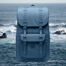 Load image into Gallery viewer, Front panel view of the blue backpack with an image of the ocean and rocks on the background.
