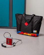 Load image into Gallery viewer, The black tote bag arranged with a tape player and lockers.
