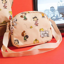 Load image into Gallery viewer, The Peanuts pattern crossbody bag leaning on a red background with Peanuts imagery on an old TV.
