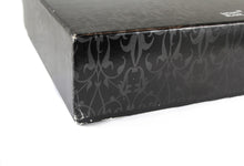 Load image into Gallery viewer, Close up to the outer box, showing signs of aging and a dent on the corner
