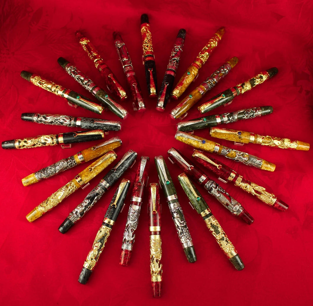 Montegrappa Chinese Zodiac fountain pen collection displayed in a circular layout on red fabric, featuring luxury handcrafted pens with gold and silver overlays representing the 12 zodiac animals.