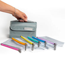 Load image into Gallery viewer, A hand holding the main bag with the six pouches fanned out in front.
