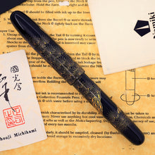 Load image into Gallery viewer, Decorative fountain pen on a paper background with the artist card.
