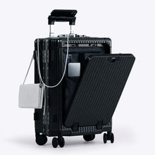 Load image into Gallery viewer, Angled front view of the black carry-on suitcase with the front panel opened. It is arranged with a charging cellphone, a small purse, and a laptop in its compartment. 
