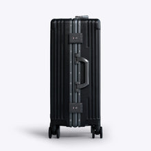 Load image into Gallery viewer, Side panel view of the black suitcase. It features a grab handle and two TSA approved three-digit combination locks. 
