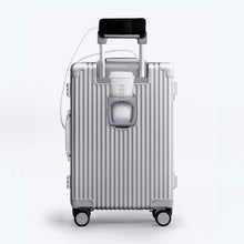 Load image into Gallery viewer, Back panel view of the silver colored suitcase showing a phone held by the telescopic handle, and a hot drink in the cup holder. 
