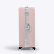Load image into Gallery viewer, Side panel view of the pink suitcase with silver-colored accents. It features a grab handle and two TSA approved three-digit combination locks. 
