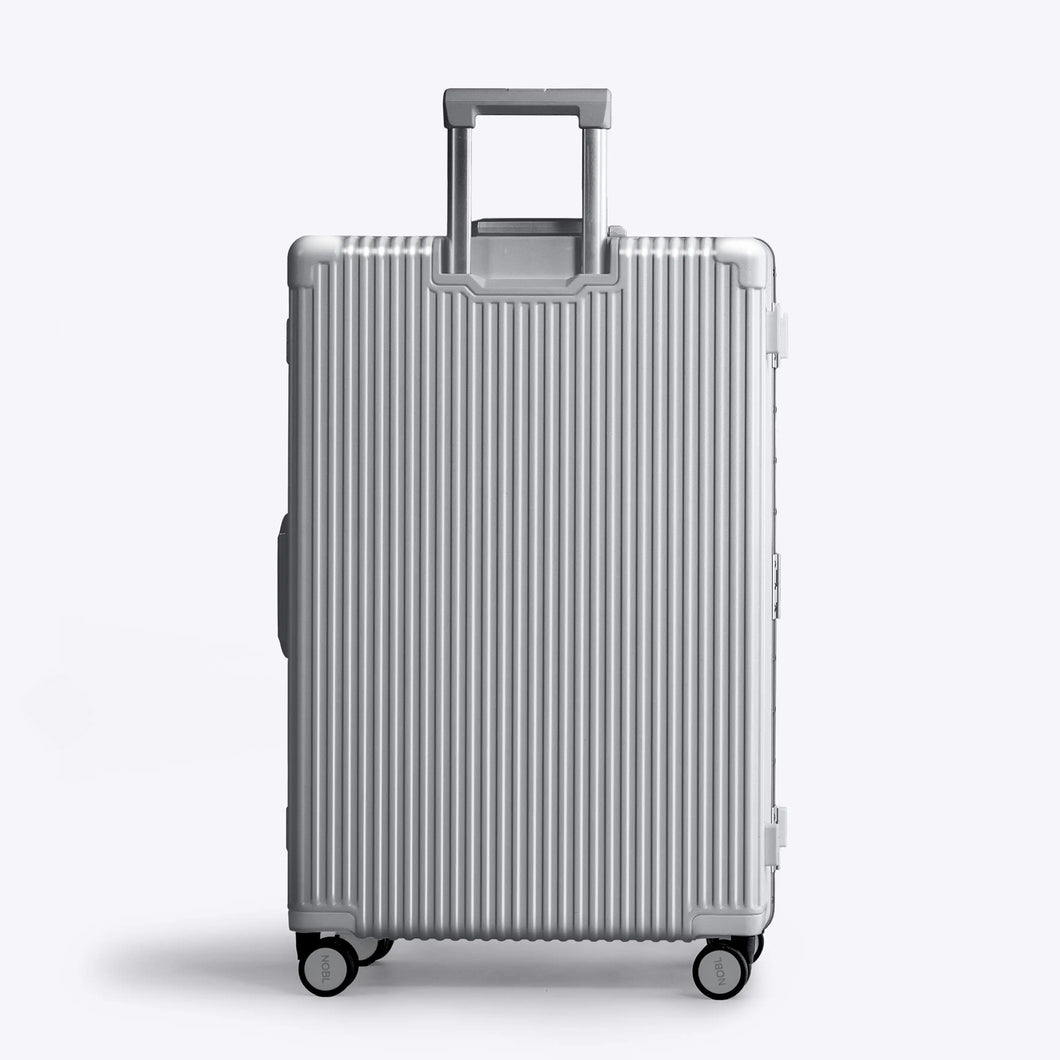 Back panel view of the silver suitcase. The telescopic handle is extended. 
