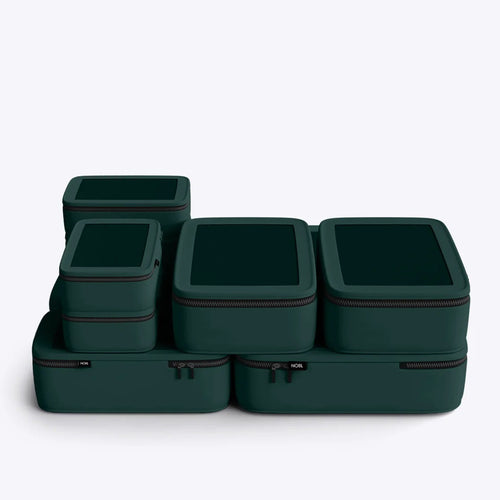 Set of dark green packing cubes with zippers on a light gray background