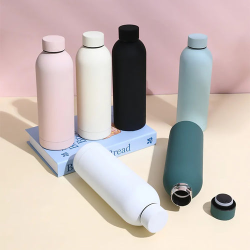 Set of colorful water bottles on a pink and beige background