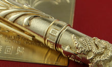 Load image into Gallery viewer, Gold pen with intricate design on a red background.
