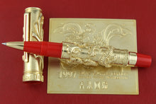 Load image into Gallery viewer, Luxury pen with gold accents and red accents on a red background.

