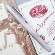 Load image into Gallery viewer, Side view of the fountain pen, arranged with the included booklets. 
