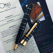 Load image into Gallery viewer, The rollerball pen arranged with the cap on top of the included pamphlets. 
