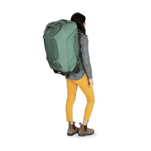 Load image into Gallery viewer, Back view of a young woman carrying the koseret green travel back with the shoulder straps.
