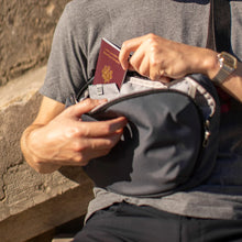 Load image into Gallery viewer, A young man placing his passport inside an RFID compartment in the sling bag.
