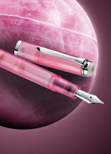 Load image into Gallery viewer, The fountain pen with the cap next to it. Set on a graphic with a round rose quartz stone.

