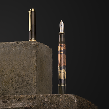 Load image into Gallery viewer, Fountain pen with decorative cap on a concrete block against a black background.

