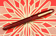 Load image into Gallery viewer, Front view of the Fountain Pen with the cap on. The clip has engraved &quot;Platinum&quot; on it. 
The pen is placed on a vibrant red background with golden decorations in the shape of a flower. 
