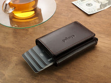 Load image into Gallery viewer, Angled view of the Pularys Boston wallet in brown on a brown wooden table. There is a glass tea cup and a $20 bill next to it.
