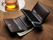 Load image into Gallery viewer, Angled view of the Pularys Boston Brown leather wallet with the card case showing the cards propped out. There is a $20 bill peeking from the cash compartment, and a tea cup set behind the wallet. 
