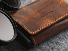 Load image into Gallery viewer, Angled close up to the brown wallet with pularys logo embossing. 
