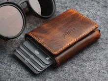 Load image into Gallery viewer, Angled view of the brown wallet with six credit cards peeking from the side. 
