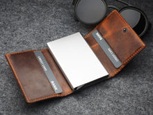 Load image into Gallery viewer, The wallet unfolded with two credit cards tucked in the leather pockets. 
