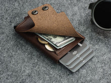 Load image into Gallery viewer, Angled view of the brown wallet with cash, coins, and cards tucked in the compartments. 

