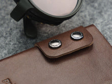 Load image into Gallery viewer, Close up to the double button snap closure on the brown wallet. 
