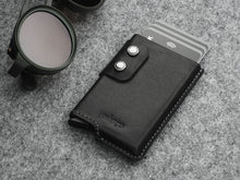 Load image into Gallery viewer, Angled front view of the black wallet with double snap closure. Six credit cards peek from the top of the wallet. 
